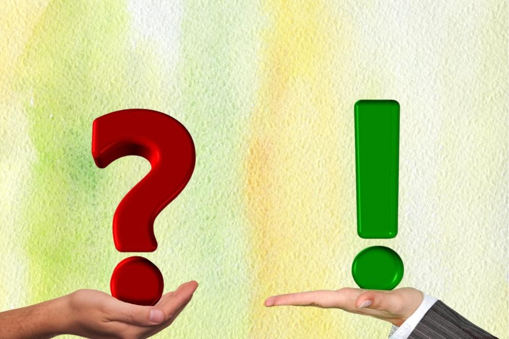 Das Foto zeigt auf der linken Seite eine Hand mit einem roten Fragezeichen und auf der rechten Seite eine Hand mit einem grünen Ausrufezeichen.