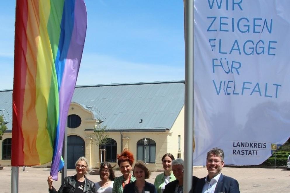 Das Foto zeigt Landrat Prof. Dr. Dusch mit Vertreterinnen aus verschiedenen Bereichen des Landratsamtes Rastatt beim Hissen der Flagge der Vielfalt.