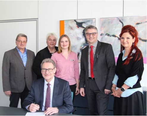 Landrat a.D. Jürgen Bäuerle unterzeichnet die Charta im Beisein von Manfred Großmann, Personalchef, Franz Herr, Per-sonalratsvorsitzender, Michaela Schmidt, Beauftragte für Chancengleichheit, Petra Mumbach, Beauftragte für Menschen mit Behinderung, und Tamina Hommer, Integrationsbeauftragte. Das Foto zeigt Landrat a.D. Jürgen Bäuerle (vorne sitzend), wie er die Charta im Beisein von Manfred Großmann, Personalchef, Franz Herr, Personalratsvorsitzender, Michaela Schmidt, Beauftragte für Chancengleichheit, Petra Mumbach, Beauftragte für Menschen mit Behinderung, und Tamina Hommer, Integrationsbeauftragte (alle dahinter stehend) unterzeichnet.